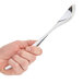 A hand holding a Sabert disposable silver plastic serving spoon.