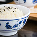 A white Thunder Group Lotus melamine rice bowl filled with rice and black sesame seeds.