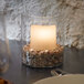 A Sterno glass votive candle holder with a lit candle on a table.