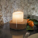 A Sterno glass votive candle holder with a lit candle inside on a table.