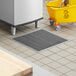 A yellow mop bucket on a tile floor with a floor drain.