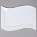 A white Fineline Wavetrends plastic luncheon plate with a curved edge on a gray surface.