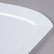 A close up of a white Fineline rectangular luncheon plate with a curved edge.