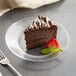 A clear plate with a slice of Ghirardelli chocolate cake and a strawberry on top.