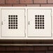 Three Winholt white metal lockers on a brick wall.