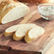 A loaf of bread on a cutting board with a bowl of flour.