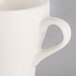 A close-up of a Tuxton Europa eggshell white espresso cup with a handle.