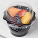 A clear dome lid on a plastic container filled with fruit.