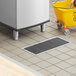 A floor trough with a grate and a yellow bucket on the floor.