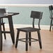 A Lancaster Table & Seating rustic industrial dining side chair with slate gray finish next to a table.