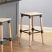 Two Lancaster Table & Seating Rustic Industrial Backless Bar Stools with white washed wood seats next to a kitchen counter.