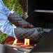 A person wearing SafeMitt oven mitts cooking burgers on a grill.