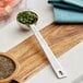 A Vollrath stainless steel round measuring spoon with a green leaf on it.