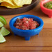 A blue Choice Thermal Plastic Molcajete bowl of salsa and limes on a table.