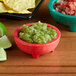 A red Choice Thermal Plastic molcajete bowl filled with salsa and chips.