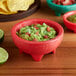 A red Choice Thermal Plastic molcajete bowl of guacamole with chips.