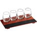 An Acopa wood flight tray with four stemless wine tasting glasses.