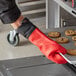 A person in red SafeMitt gloves holding a tray of cookies.