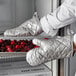 A person wearing Choice silicone oven mitts holding a tray of berries.