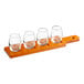 An Acopa dual-sided flight paddle with 4 stemless wine tasting glasses on a wooden tray.