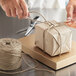 A hand tying a package with 5-Ply Natural Jute Twine.