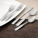 A white plate with the Walco Derby stainless steel dinner fork and knife on it.