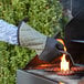 A person wearing a SafeMitt oven mitt cooking burgers on a grill.