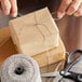 A person tying Baker's Mark black and white twine on a box.