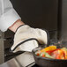A person using a SafeMitt to cook vegetables in a pan.