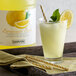 A glass of Narvon lemonade with a yellow and white striped straw and a lemon wedge with a bottle of Narvon lemonade.