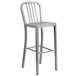 A silver metal bar height table with 4 silver metal bar stools with vertical slat backs.