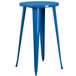 A blue round table with legs and two blue metal stools with vertical slat backs.