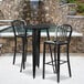 A black Flash Furniture bar table and two chairs on an outdoor patio.