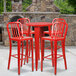 A Flash Furniture red metal table with red metal bar stools on an outdoor patio.