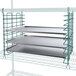 A metal tray slide holding three metal trays on a wire rack.