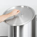 A hand using the Vollrath stainless steel cover on a pot.
