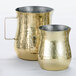 Two American Metalcraft gold hammered stainless steel bell creamers with handles.