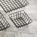 Three American Metalcraft black square wire baskets on a wood surface.