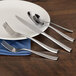A white plate with the Walco Baypoint heavy weight stainless steel dinner fork on it.