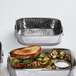 An American Metalcraft stainless steel square food serving tub holding a sandwich, vegetables, and a white liquid.