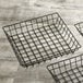 Three American Metalcraft black square wire baskets on a wood surface.