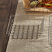 An American Metalcraft stainless steel square wire basket with food on a table.