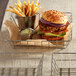 A stainless steel square wire basket with a burger and fries inside.