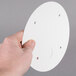 A person holding a white circular Solo paper lid.