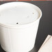 A white Solo 5 lb. food bucket with a vented paper lid on top on a table.