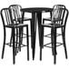 A black metal bar table with four black vertical slat back stools around it.