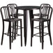 A Flash Furniture black metal bar height table with four black metal chairs with vertical slat backs.