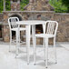 A white metal Flash Furniture bar height table with two white metal bar stools.