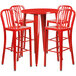 A round red metal bar table with four red vertical slat back chairs.