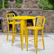 A yellow Flash Furniture bar height table with two yellow chairs on an outdoor patio.